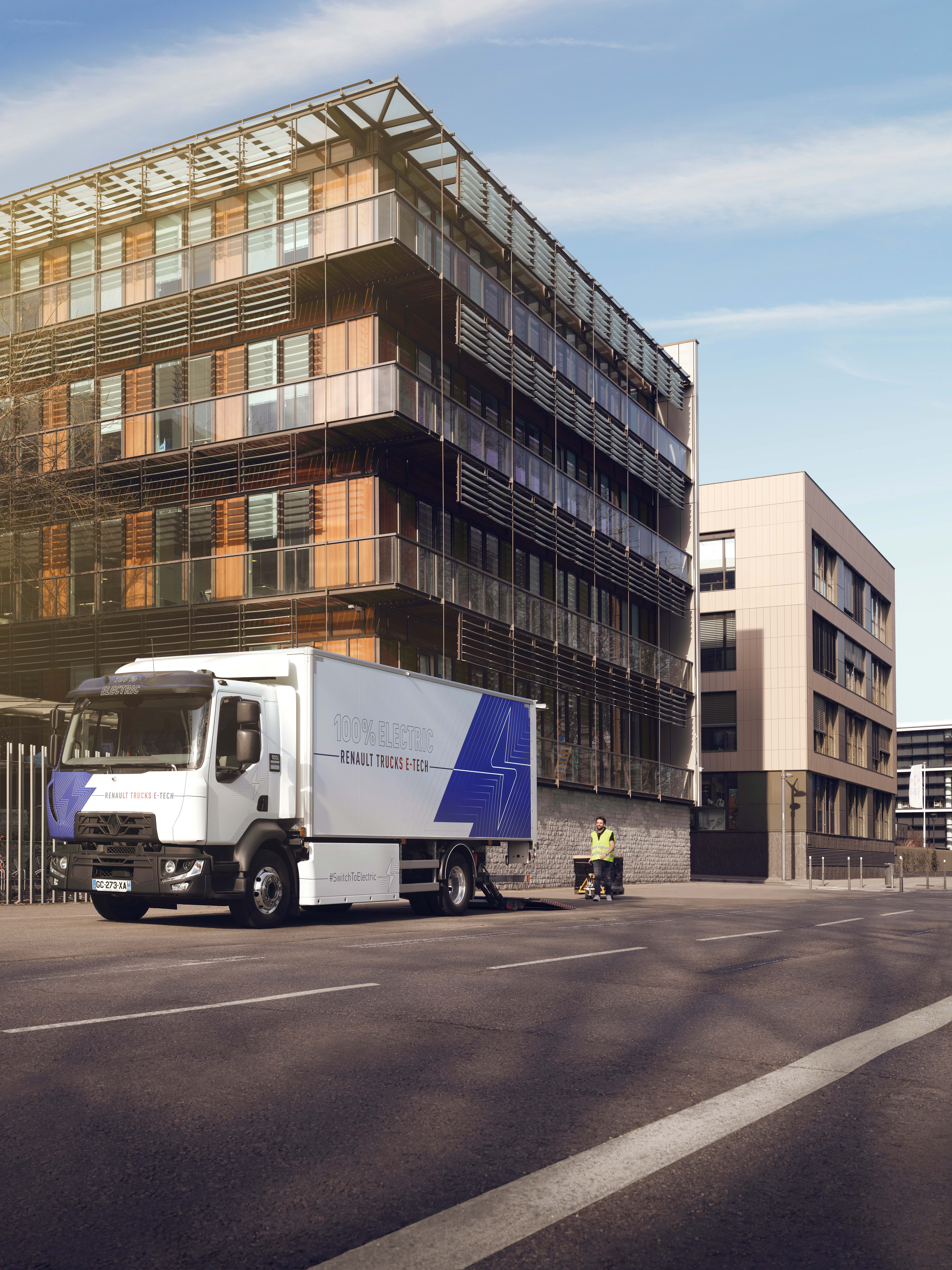 Renault Trucks D E-Tech auf der Straße vor einem modernen Wohnhaus.