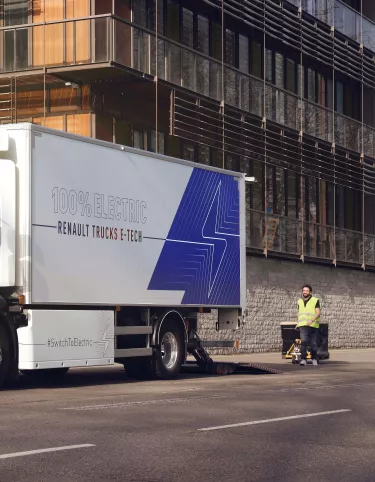 Renault Trucks D E-Tech auf der Straße vor einem modernen Wohnhaus.